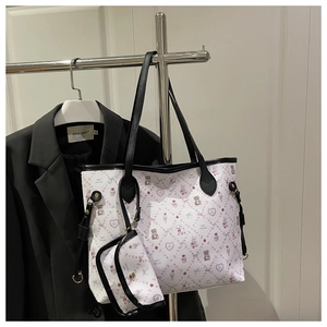 Détail du sac cabas blanc avec imprimé ours et pochette assortie sur un support argent
