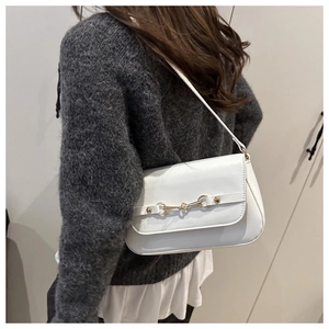 Side view of white shoulder bag with gold horsebit detail worn by a model