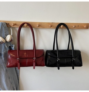 Close-up of vintage glossy patent leather shoulder bag with decorative metal buckles