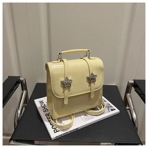 Détail d'un mini sac à dos en cuir verni jaune avec étoiles argentées sur magazine