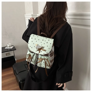 Detail of backpack with star prints, checkered fabric, and brown ribbon bow decoration