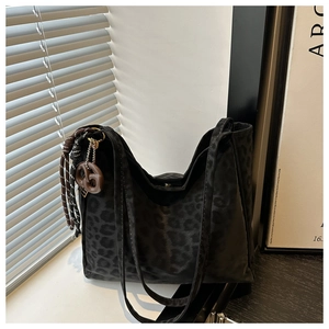 Macro shot of black leopard print suede tote with stylish resin charm and braided tassels