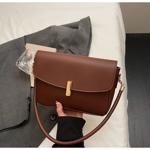 Detail view of the brown leather shoulder bag with a sleek gold rectangular lock and flap