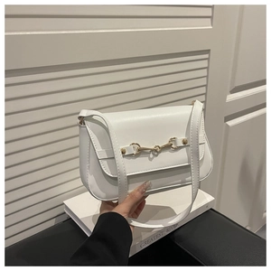 Detail of white PU leather shoulder bag with golden horsebit buckle on black leather base