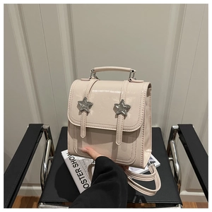 Close-up of beige glossy mini backpack with silver star buckles on a modern chair