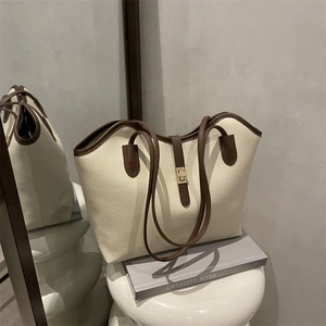 Minimalist beige pebble leather tote bag with brown belt strap and gold buckle