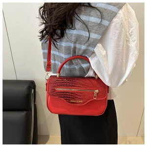 Détail du rabat rouge texture crocodile et fermeture éclair en métal du sac à main