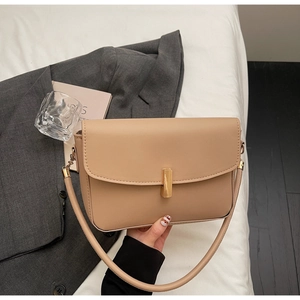 Detailed close-up of the elegant golden metal lock on a beige leather minimalist handbag