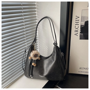 Dettaglio borsa hobo vintage nera in ecopelle con ciondolo a forma di orso e luce soffusa
