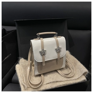 Detail of a chic cream and khaki mini backpack featuring silver star accents in a gift box