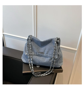 Detail of blue denim shoulder bag with silver chain strap and metal buckle clasp