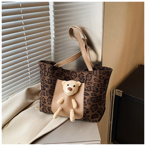Close-up of leopard print tote bag with plush bear detail and leather straps in sunlight
