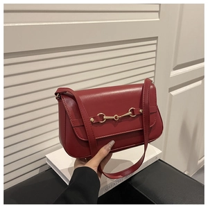 Close-up of elegant burgundy leather bag with golden horsebit buckle hardware