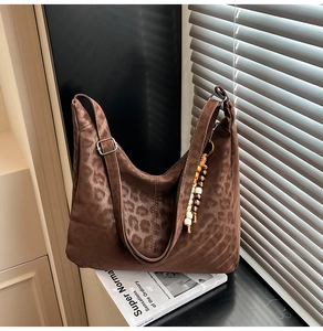 Detail of leopard print suede hobo bag with beaded tassel and silver buckle on a magazine