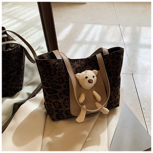 Detail of leopard print tote bag featuring a 3D plush bear and leather handles