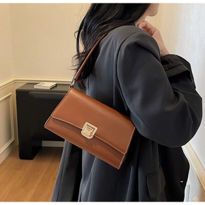 Detail of caramel brown leather underarm bag featuring a classic gold square buckle lock