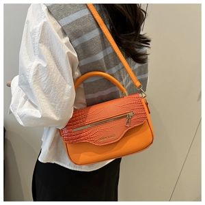 Détail du sac à main orange avec rabat à motif crocodile et accents zippés en métal