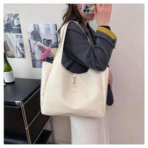Detail of elegant cream tote bag featuring golden metal buckle and premium faux leather