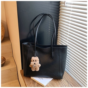 Macro shot of black tote bag with leather texture and cute brown plush puppy charm
