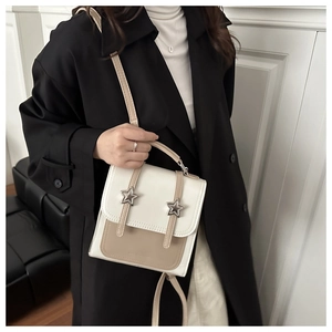 Side view of small cream and mocha contrast backpack with star buckles on model