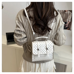 Detail of white polka dot backpack showing the flap design and casual letter print