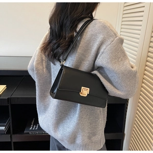 Detail of the elegant black leather underarm bag with a golden metallic buckle closure