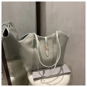 Detail of mint green tote bag featuring lychee textured leather and gold metal clasp
