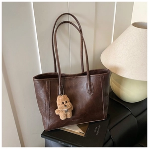 Détail du sac cabas vintage en cuir marron avec charme ours en peluche et longues anses