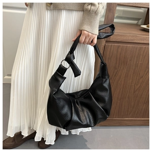 Detail of black pleated hobo bag with litchi texture and knotted shoulder strap