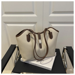 Detail of cream leather tote bag featuring a gold twist lock and brown contrast piping
