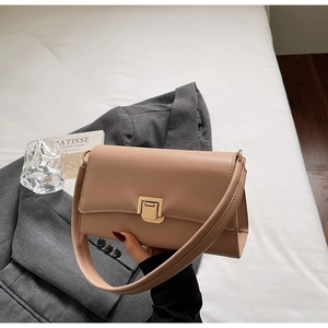 Close-up of minimalist square bag with gold lock buckle and wide shoulder strap