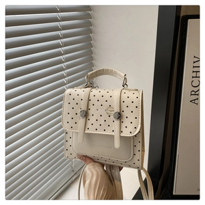 Close-up of minimalist beige handbag with black polka dots and cartoon burger graphic