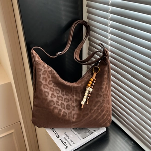 Leopard print hobo bag in faux suede with wooden beads decor near window light