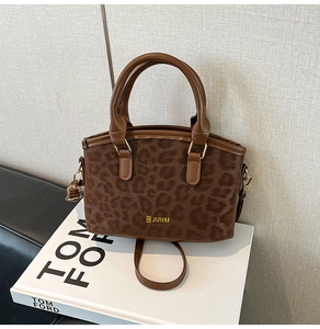 Dettaglio ravvicinato della borsa leopardata con finiture in metallo dorato e logo