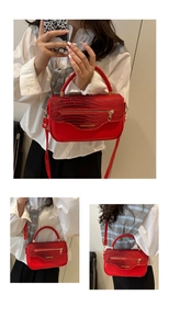 Détail du sac à main rouge à texture crocodile avec zip doré et finitions métalliques