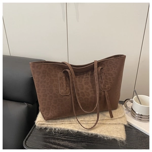 Detail of dark brown leopard print tote bag on a beige scarf with a lifestyle backdrop