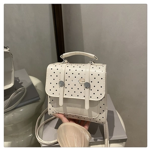 Close-up of cream PU leather crossbody bag with black dots and cartoon illustration