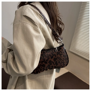 Close-up of leopard print shoulder bag with silver hardware worn on a beige trench coat
