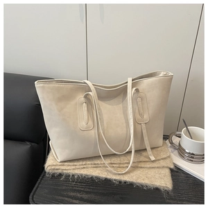 Detail view of large beige tote bag in matte soft leather on textured fabric