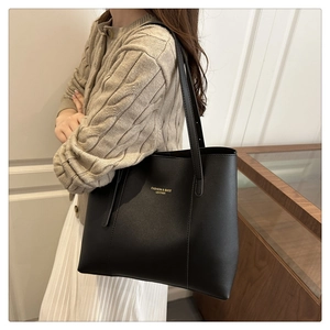 Close-up of black leather tote bag with gold lettering shown on a female model