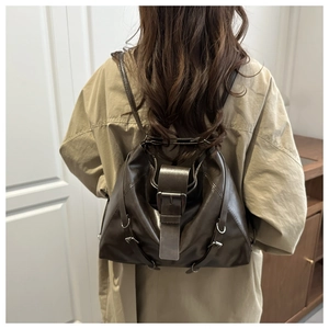 Detail of vintage dark brown leather backpack with retro metal buckle on a trench coat