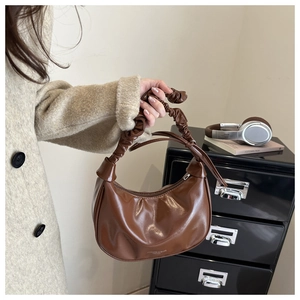 Detailed close-up of dark brown pleated dumpling bag with elegant bow accent and leather texture