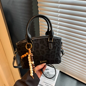 Borsa a tracolla nera leopardata con ciondolo vintage e logo dorato raffinato