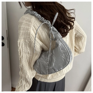 Close-up of silver metallic pleated dumpling bag with side ribbon bow detail on shoulder