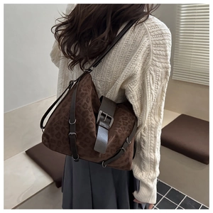 Detail of vintage leopard print shoulder bag in brown faux suede with leather strap buckles