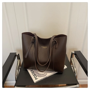 Detail of dark brown leather tote bag with FASHION & BAGS inscription on a magazine