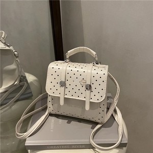 Weißer Rucksack mit Polka Dots, Burger-Motiv und Tragegriff auf Büchern präsentiert