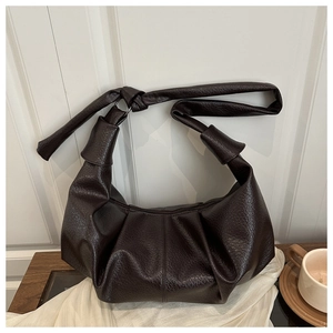 Détail du sac hobo en cuir marron foncé avec bandoulière nouée et design plissé