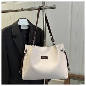 Detail of cream tote bag featuring brown contrast straps and fashion brand label tag