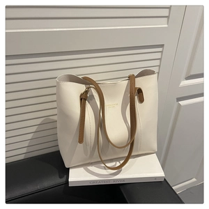Detail of cream tote bag with brown leather straps and gold embossed lettering